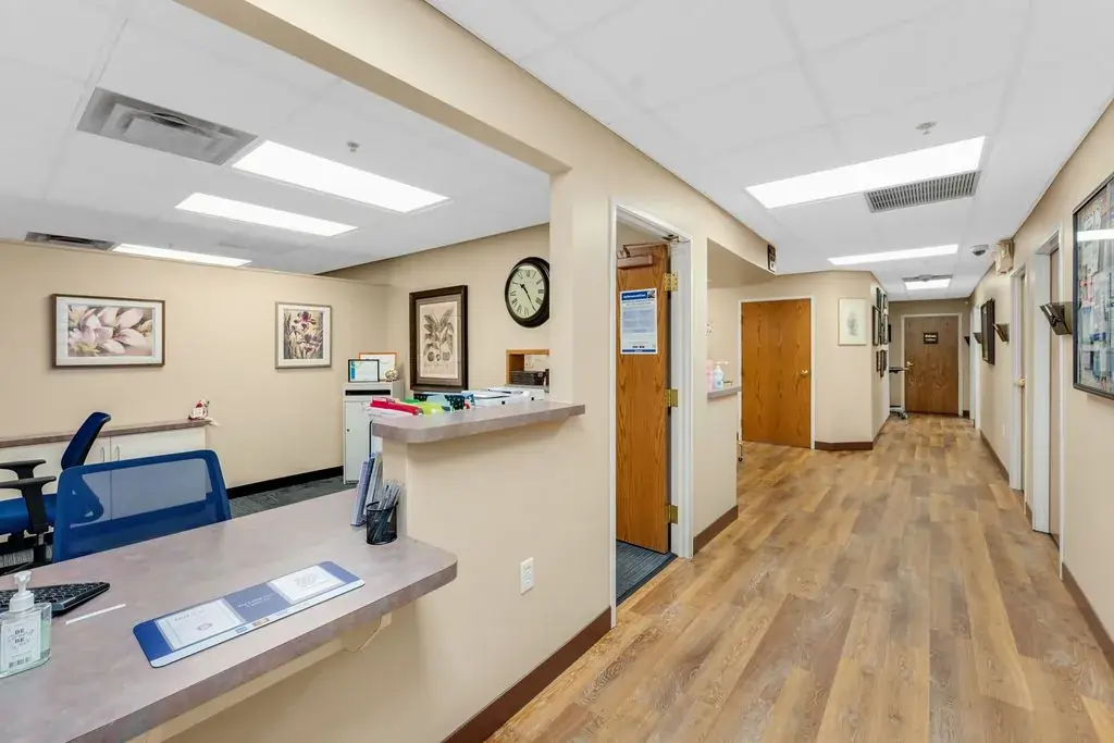 Clean, professional medical office reception with wood-style floors and framed wall art.